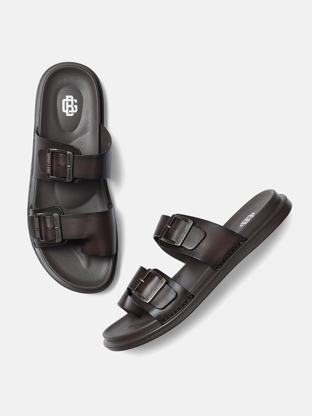 A pair of dark brown men's sandals with adjustable buckle straps and flat heels.