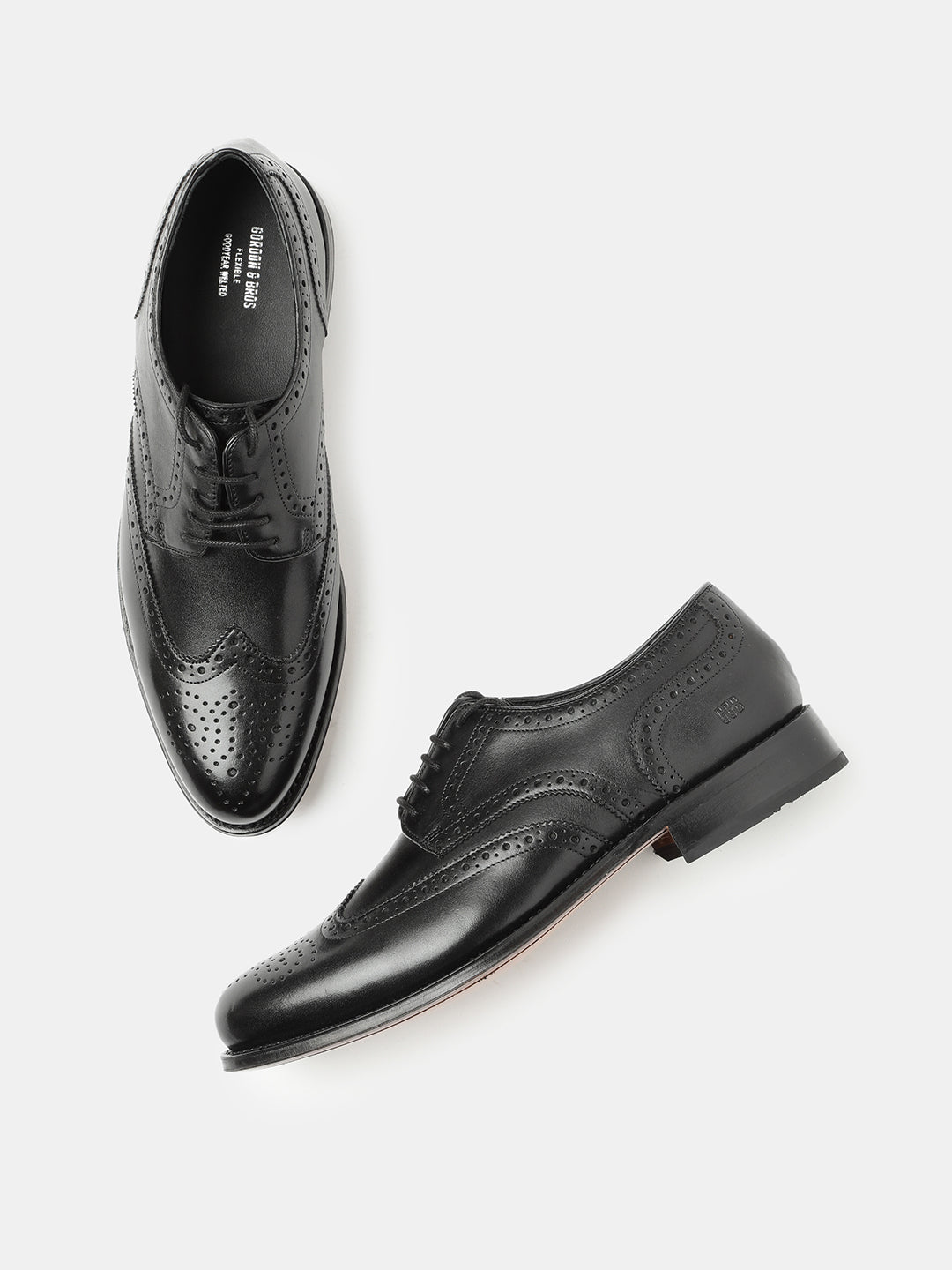 A pair of black leather wing brogue lace-up shoes on a white background.