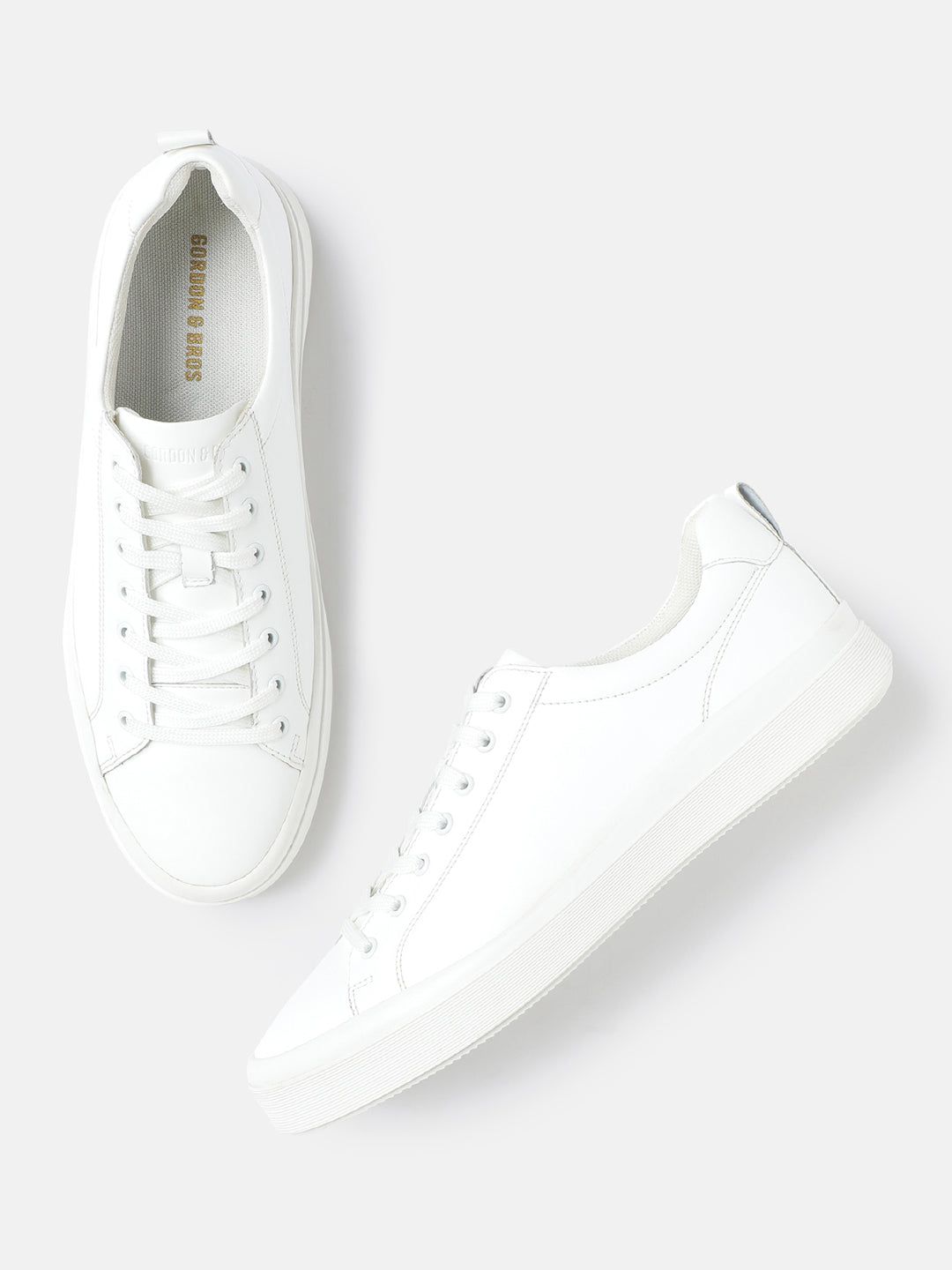 A pair of white men's lace-up sneakers by GORDON & BROS, displayed against a white background.