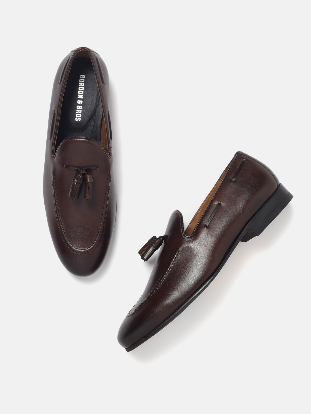 A pair of brown leather loafers with a lace-up closure and a tassel detail on the vamp.