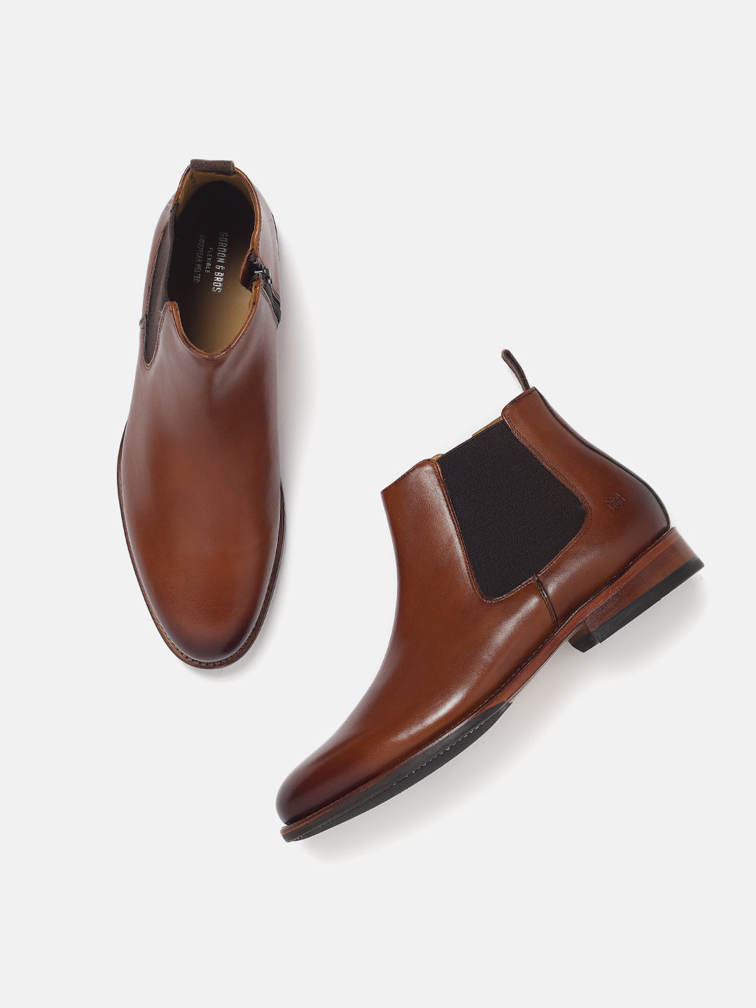 A pair of brown Chelsea boots with elasticated entry and a pull tab, featuring a leather inlay sole and a soft textile lining.