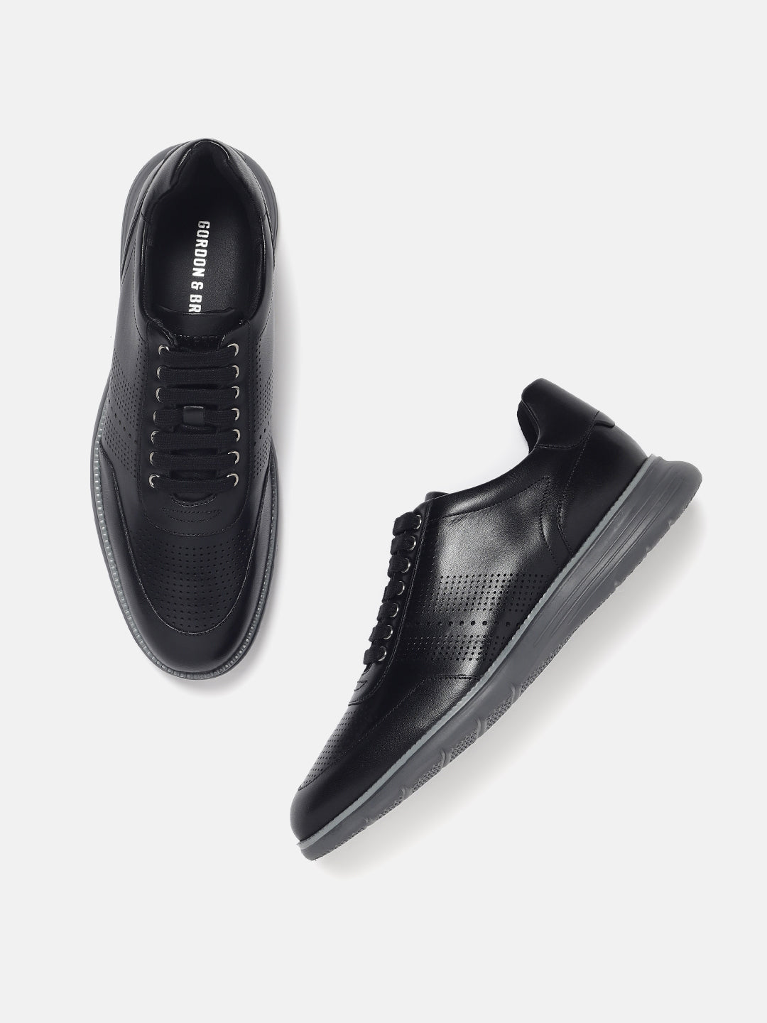 A pair of black leather lace-up sneakers on a white background.