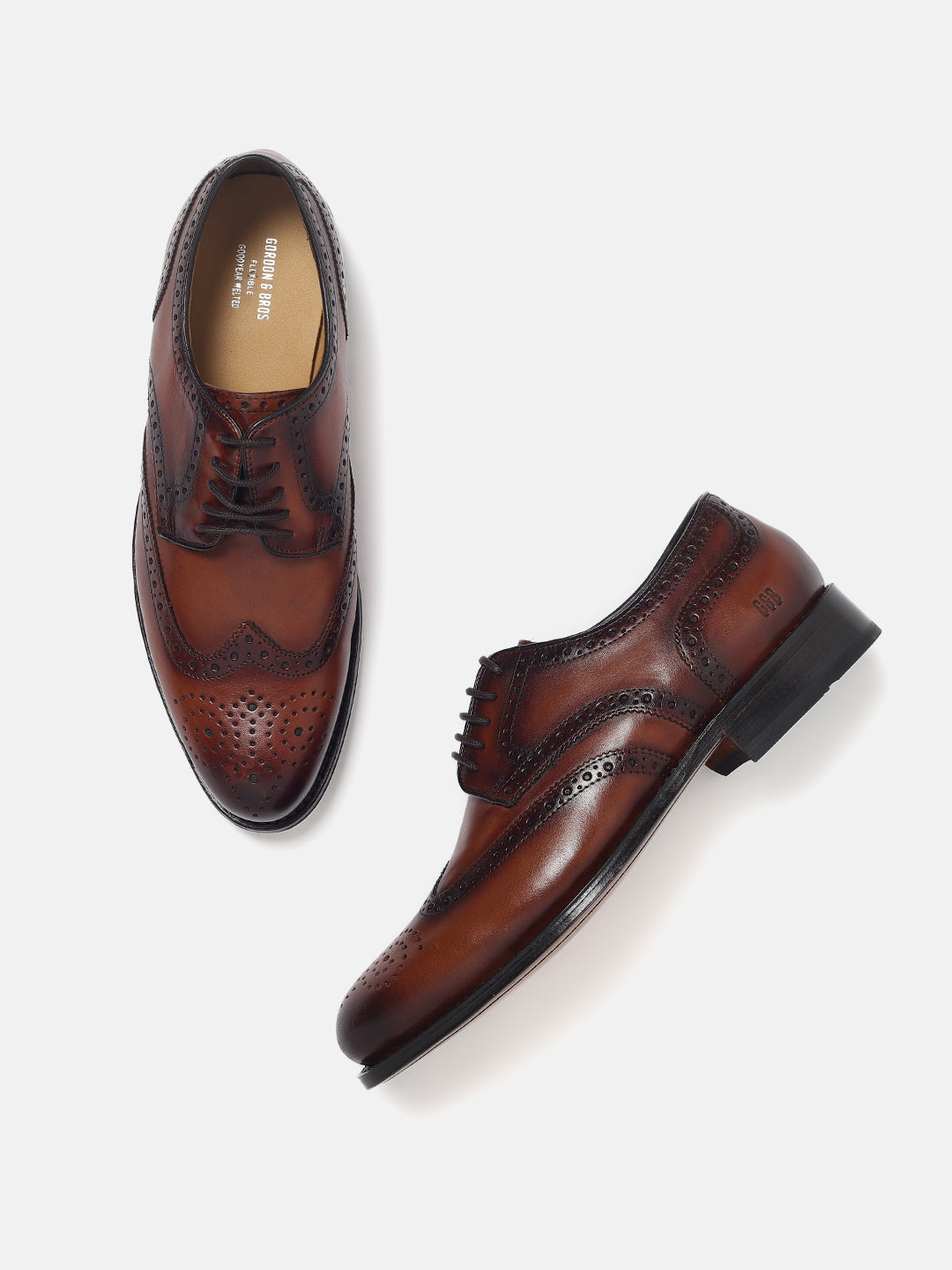 A pair of brown leather brogues with lace-up closure and a contrasting color sole.