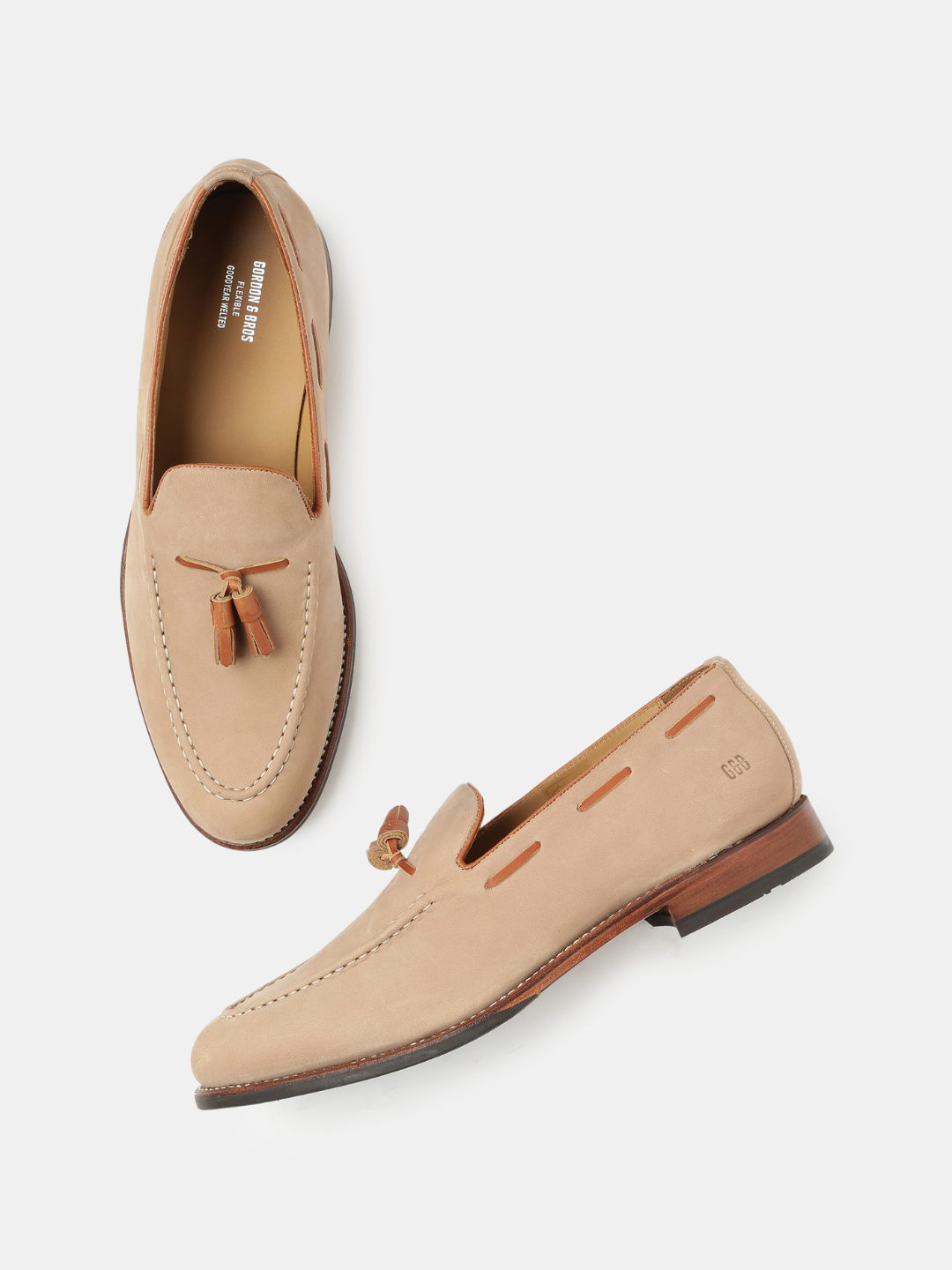 A pair of beige men's leather tassel loafers with a buckle closure and bow detail.
