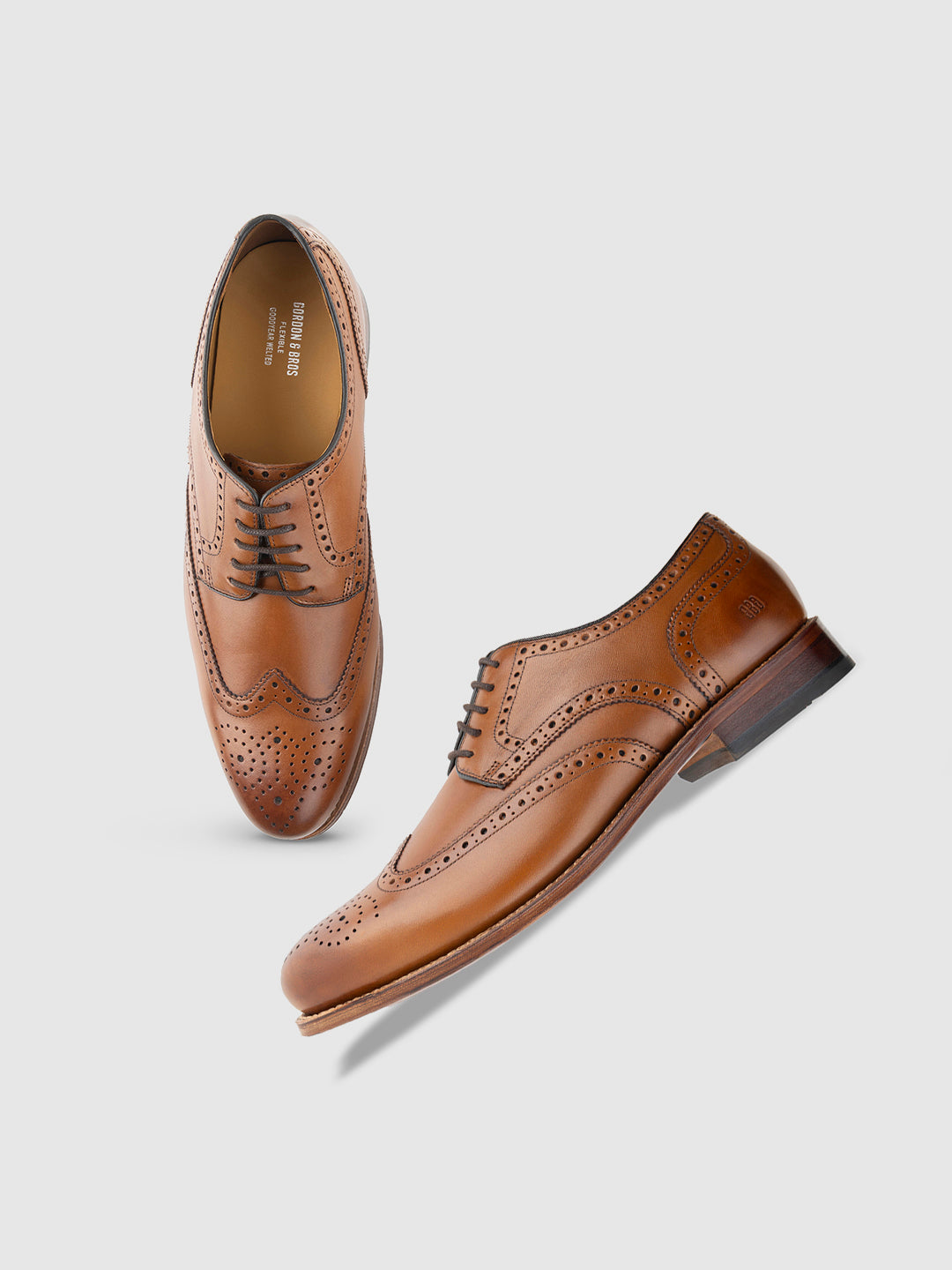 A pair of tan, lace-up, brogue-style leather loafers displayed against a white background.