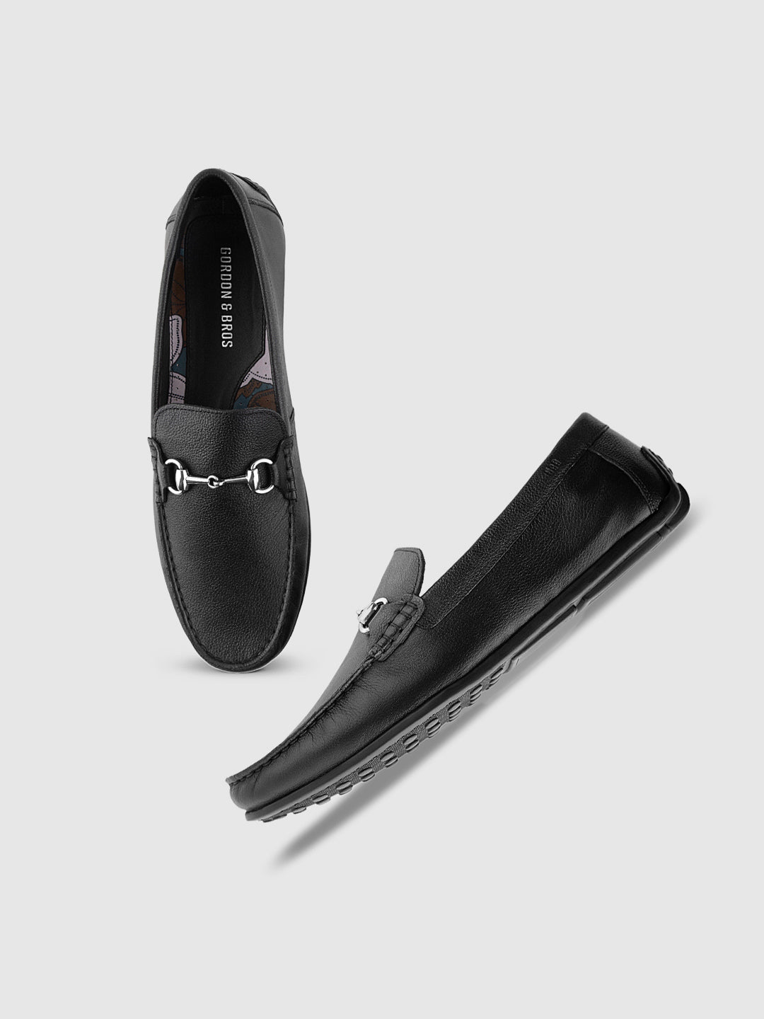 A pair of black men's moccasin loafers with a metallic buckle on the strap, offered on a white background.